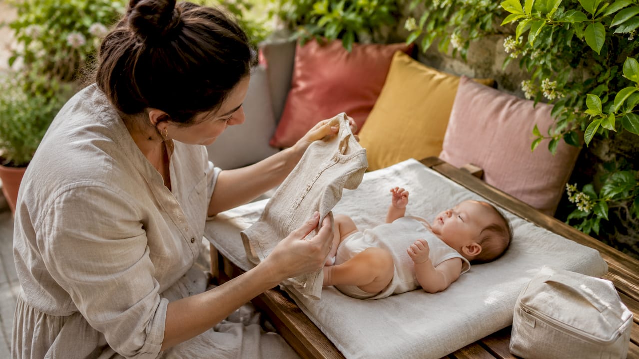 Mother dressing baby in linen clothing
