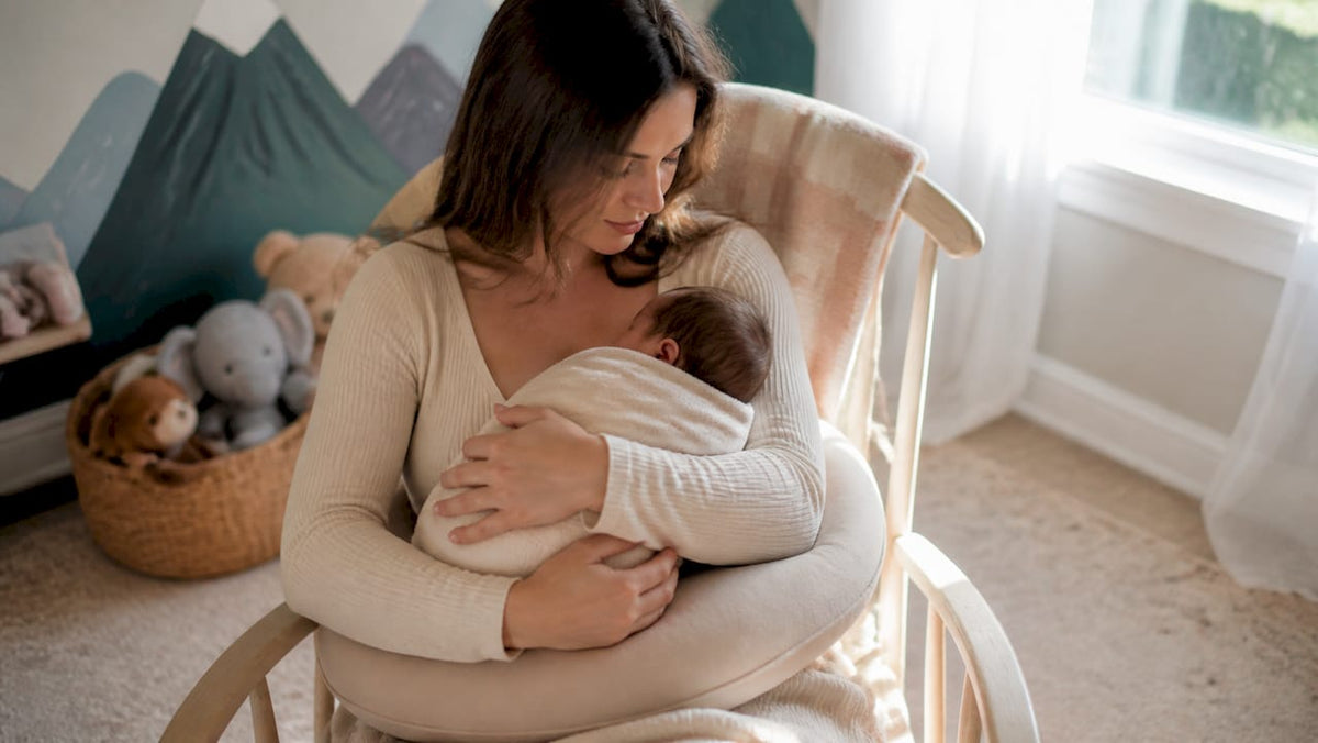 Mother supporting newborn with ergonomic nursing pillow