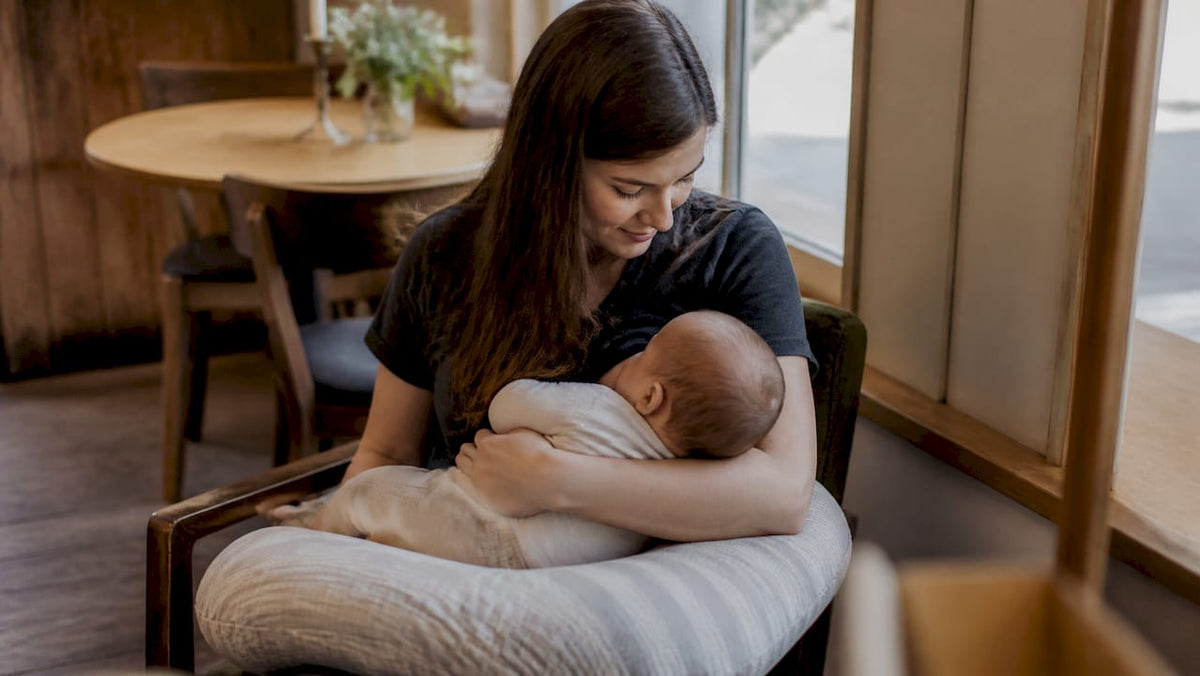 Mother holding baby with nursing pillow support