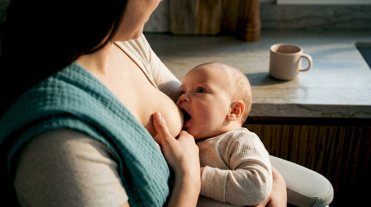 Mother guiding baby toward breast for latch