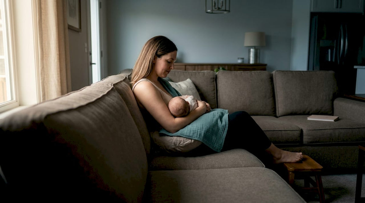 Mother breastfeeding upright on a couch